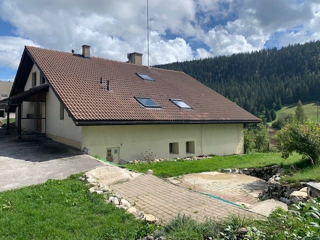 2 story house, brown roof, white walls, solar panels, parking, driveway, green lawn, mountains in the background