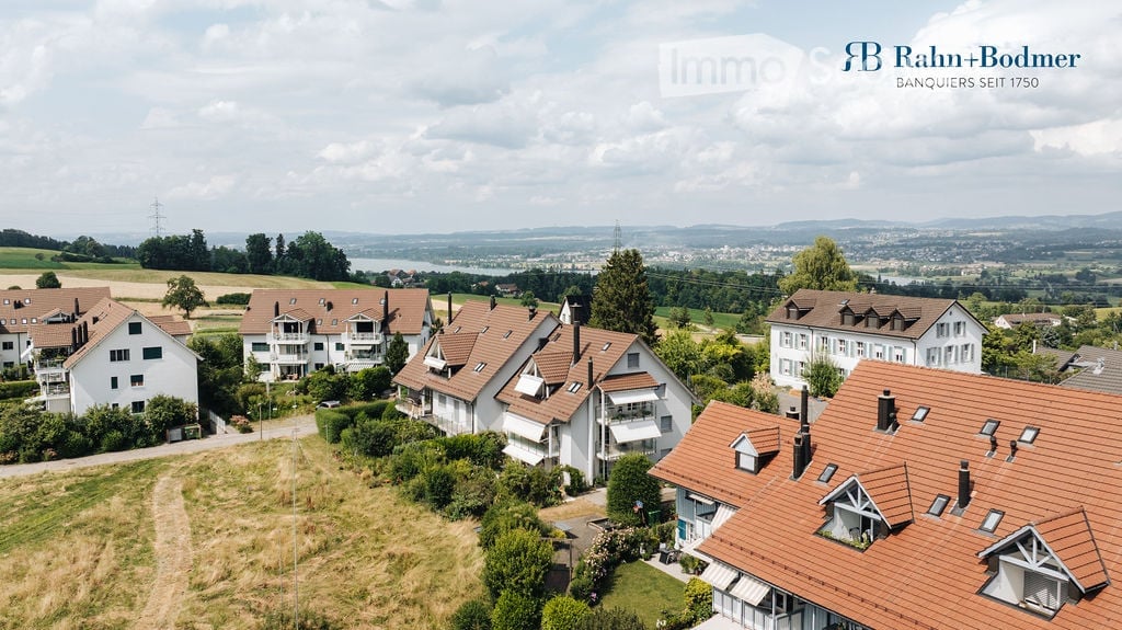 cluster of residential houses, red roofs, white walls, hilly landscape, valley view, greenery