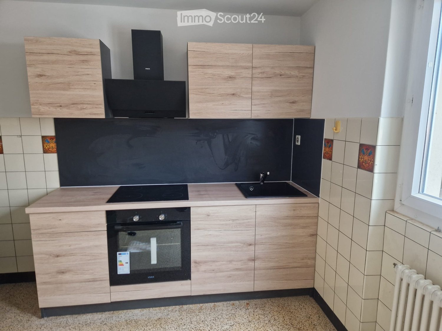 Modern kitchen with wooden cabinets, black countertops, gas stove, oven, sink, white tiled backsplash