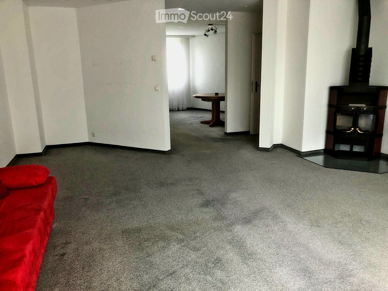 empty living room, fireplace, wooden table, gray carpet, red couch