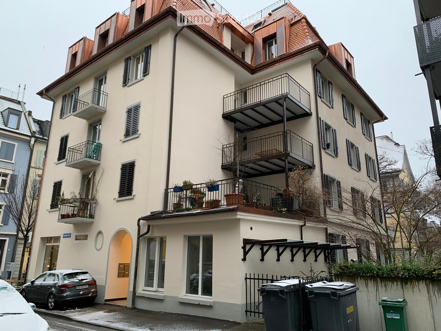 White house, brick walls, multiple balconies, red tiled roof, black shutters