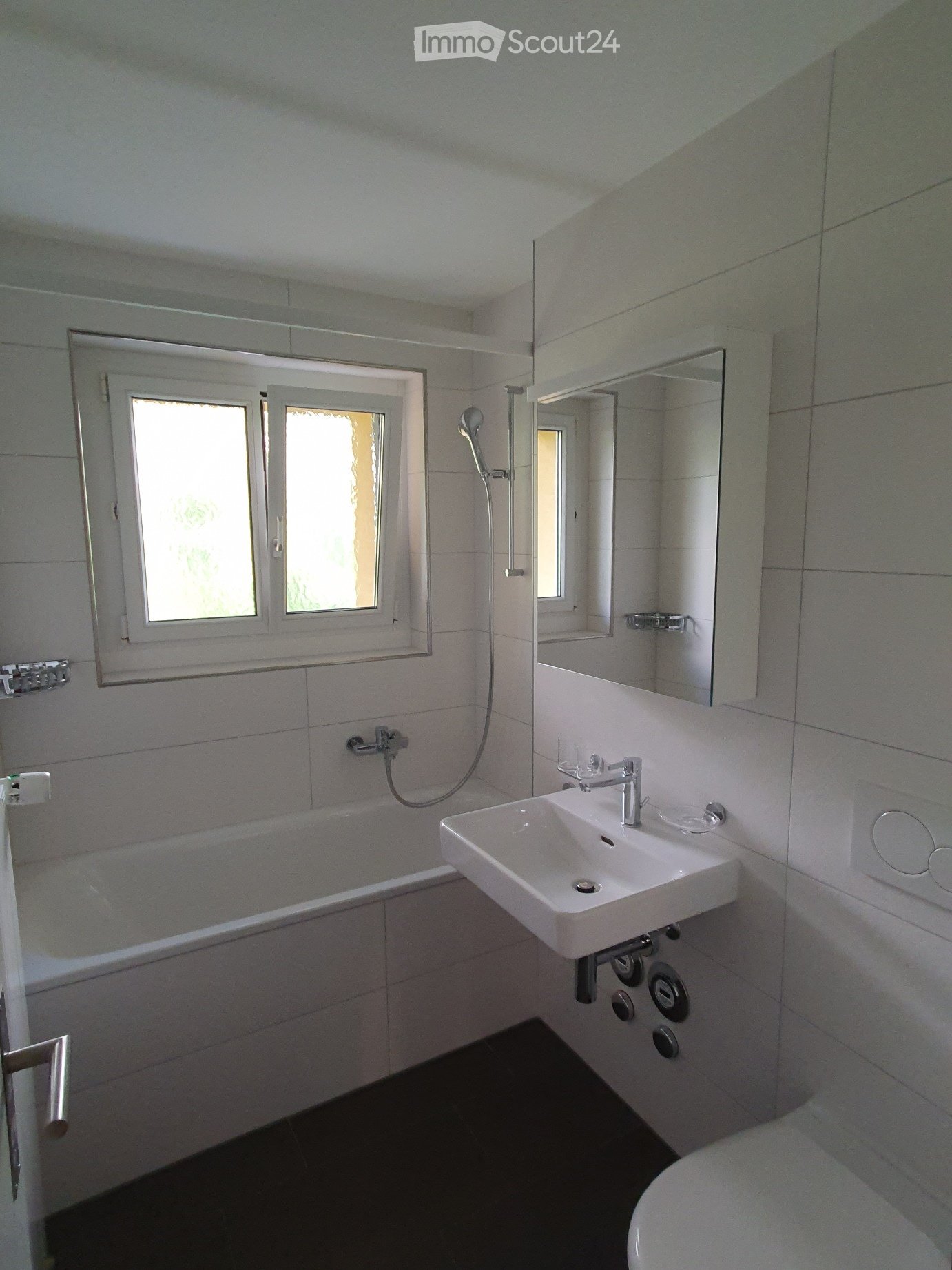 Bathroom with white bathtub, sink, and toilet, white tiles, large mirror, shower head