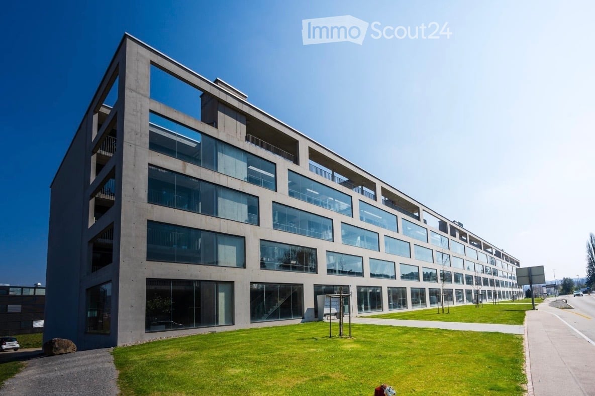 large modern office building, many windows, concrete exterior, paved walk