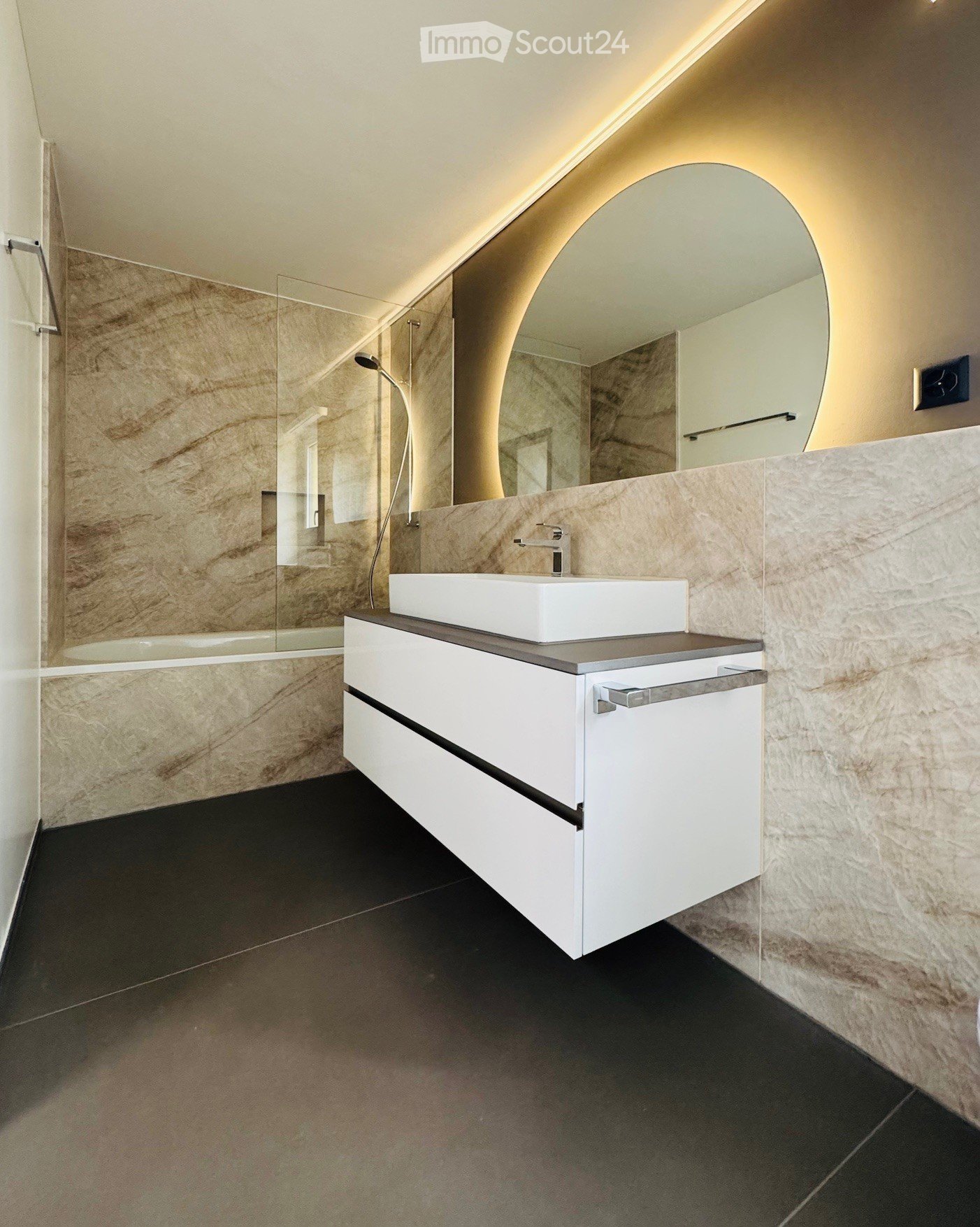 Modern bathroom, white vanity with sink, marble walls, glass shower, bathtub
