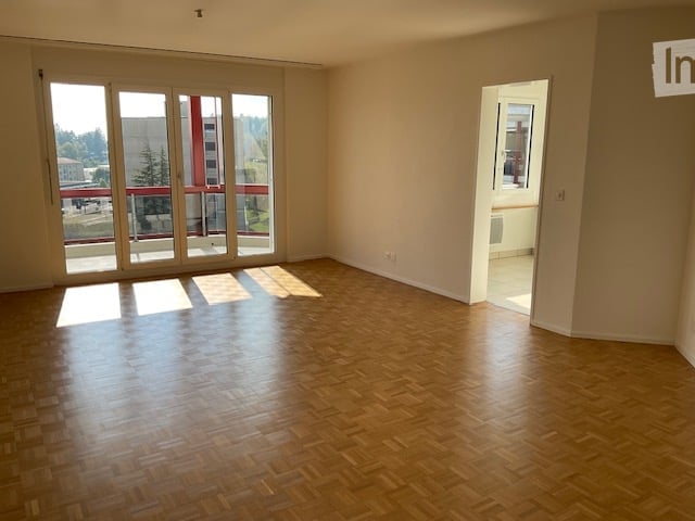 large room with sliding glass doors, balcony, wooden floor, white walls