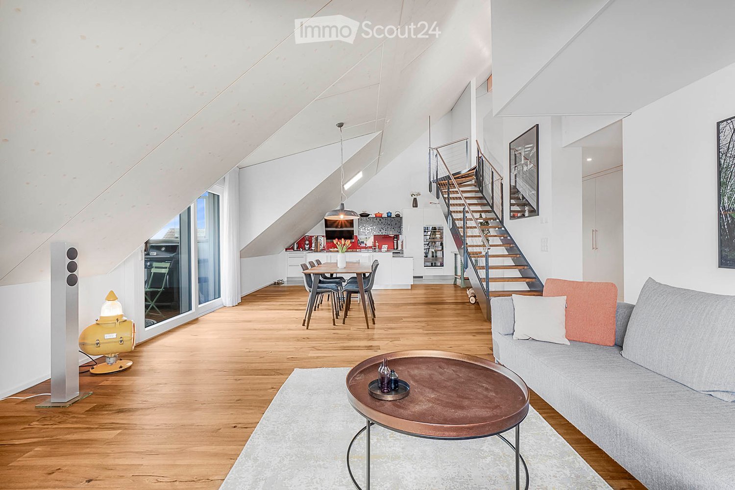 open layout, hardwood floor, white walls, dining table, sofa, staircase, coffee table, side lamp, windows