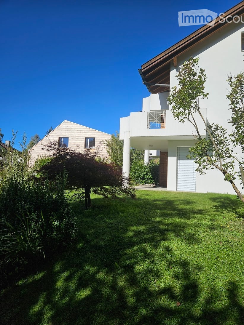 White house, brown roof, garage, trees, well-maintained lawn