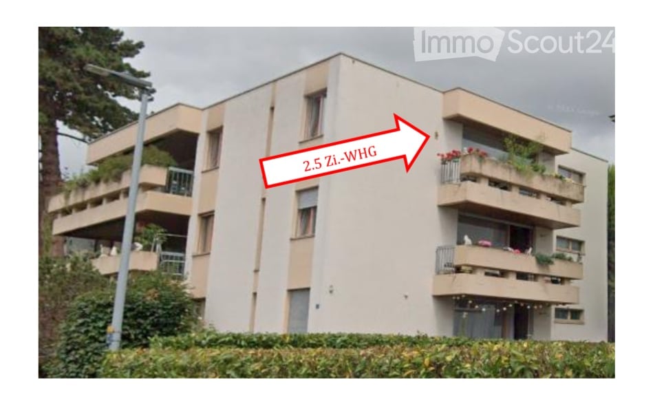 A multistory apartment building, white exterior, multiple balconies, street light in front.
