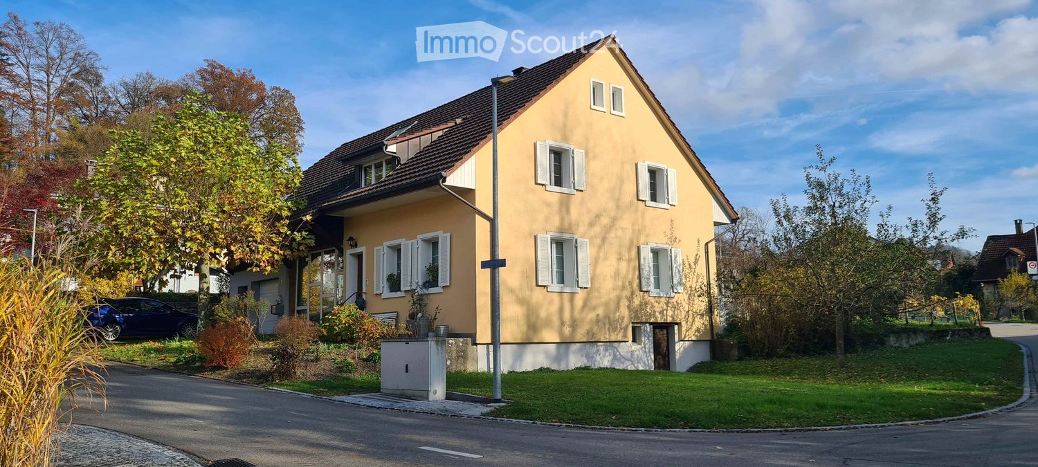Raised ground floor, yellow exterior, brown roof, 4 windows, front garden, street view