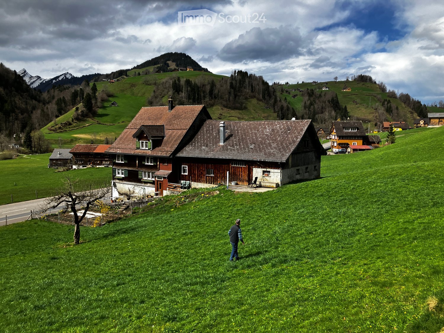 Traditional wooden house, situated in a green mountainous area, surrounded by grassy hills and mountains