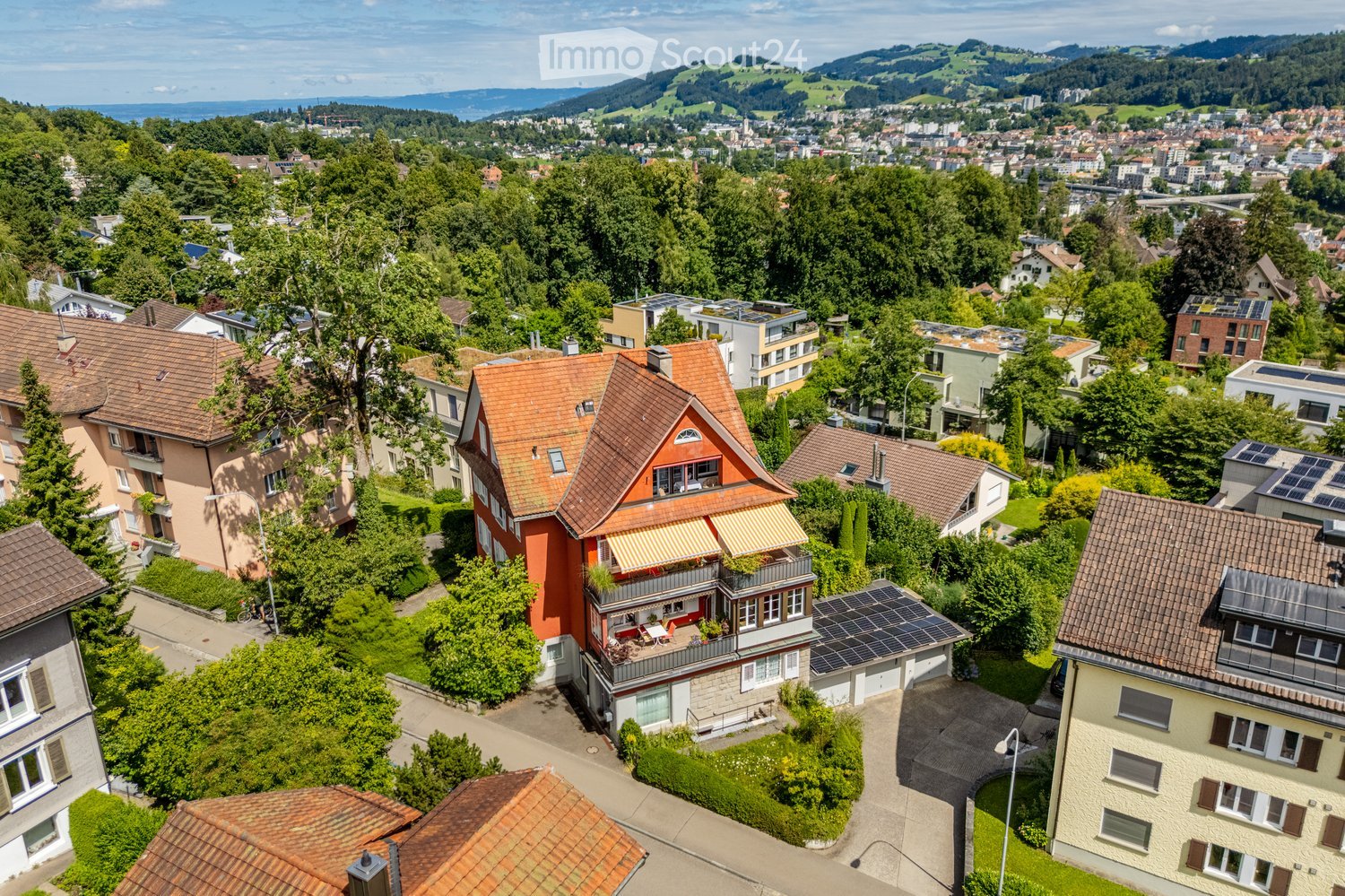 2 story house, orange exterior, terrace on the top floor, solar panels on the roof, detached garage