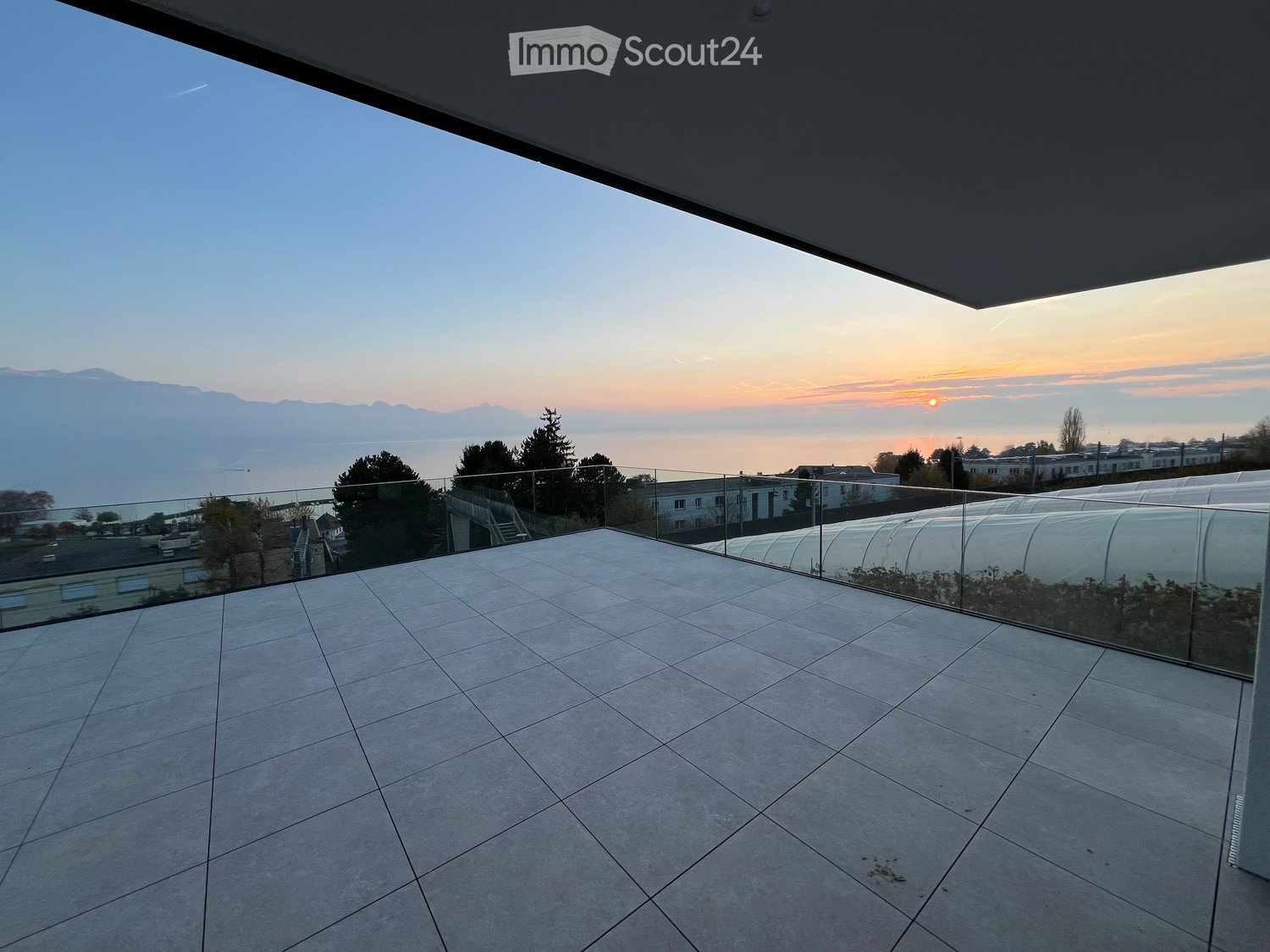 open space, concrete flooring, glass railings, scenic view of sunset and horizon