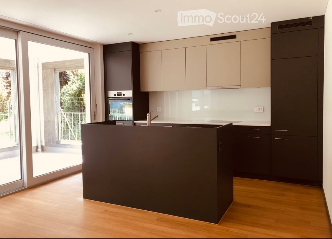 modern kitchen, large island, built-in oven, integrated refrigerator, wooden floors, sliding glass doors leading to balcony