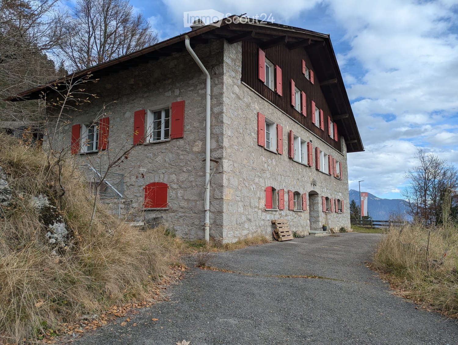 Stone exterior, red shutters, steeple roof, road, mountains in the background