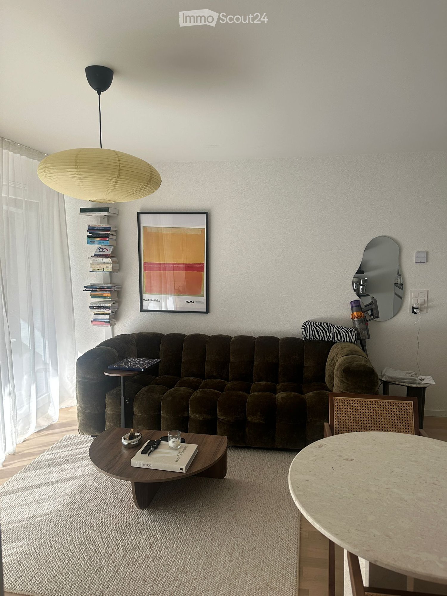 Velvet couch, coffee table, carpet, round table, armchair, framed art, bookshelves, pendant light