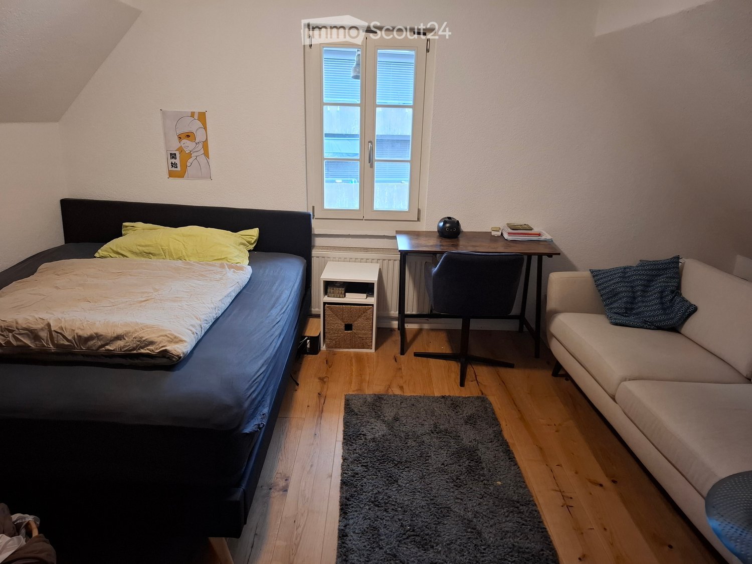 Small room with bed, desk, and couch. Windows have blinds.