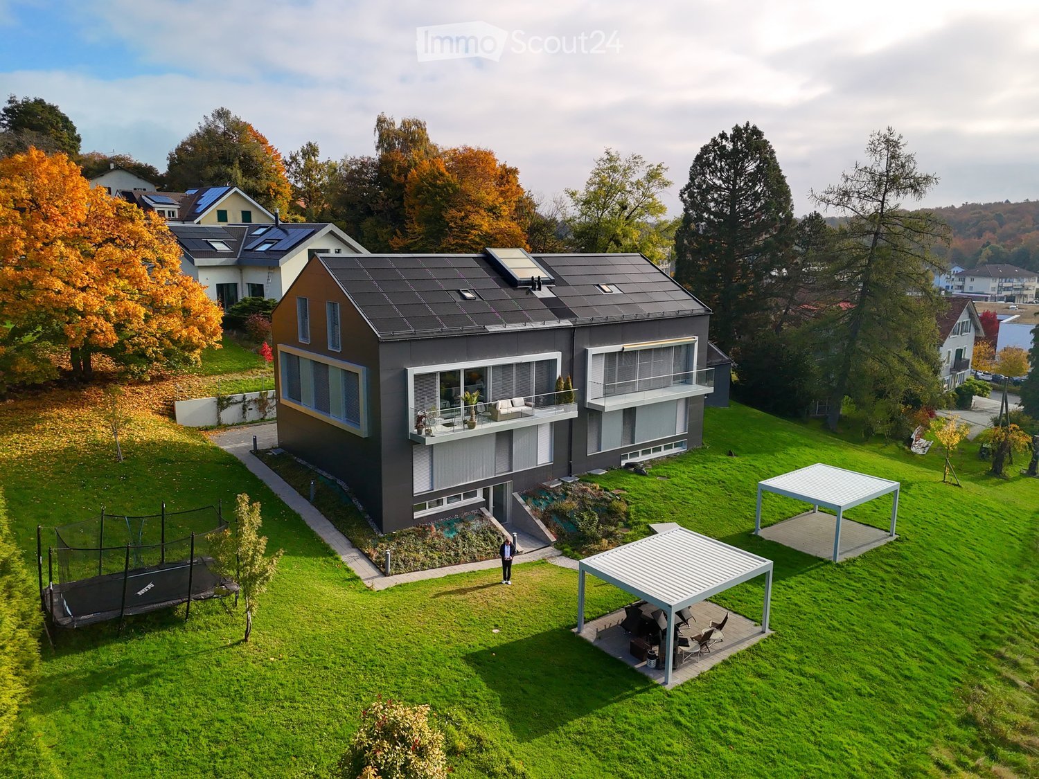 modern house, large front yard, solar panels on roof, open gazebo, trampoline, paved walkway