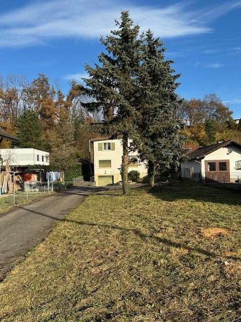 a house with multiple stories, surrounded by trees and shrubs