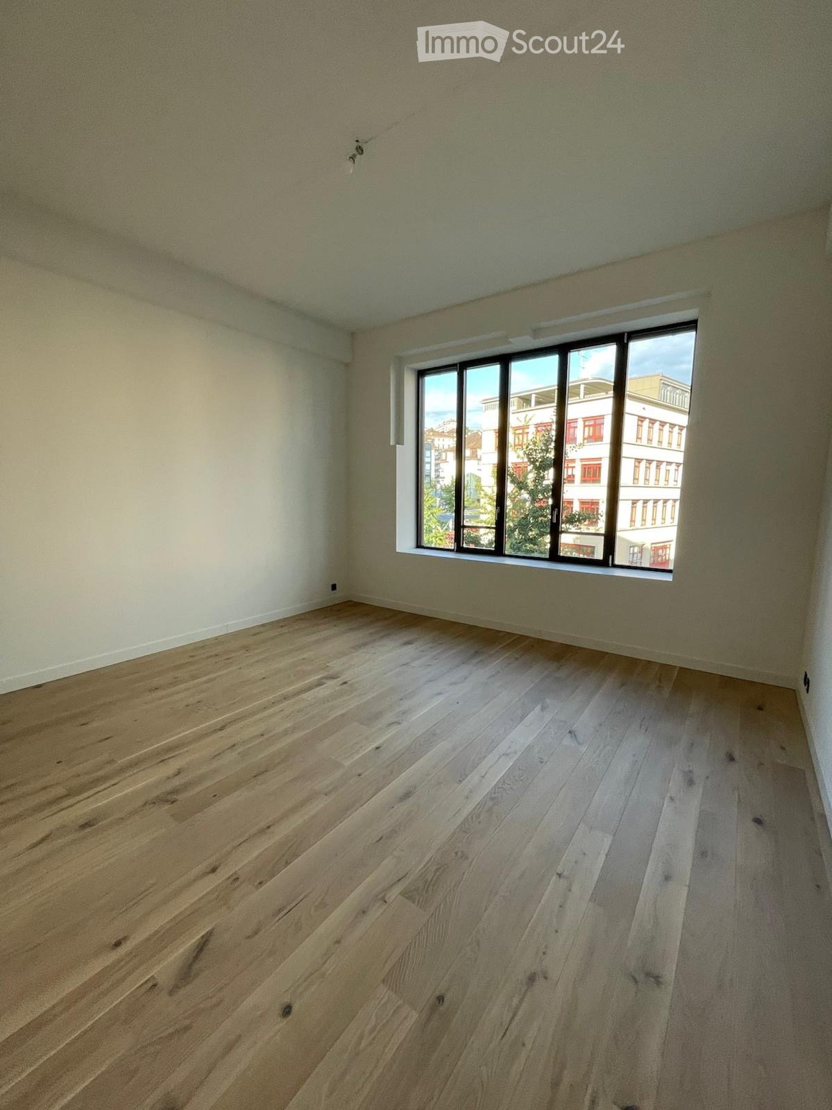 empty room, hardwood floor, large window, view of a building outside