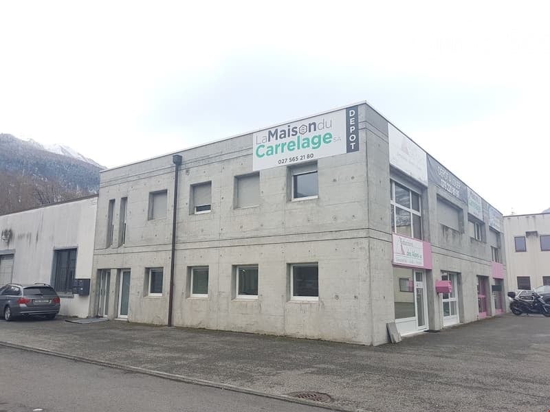 large gray building, multiple windows, car parked in front