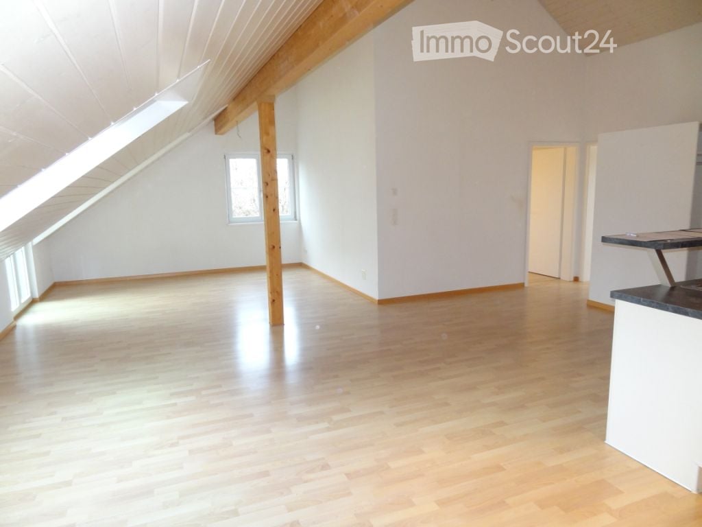 empty attic with wooden floor, white walls, beams, and windows