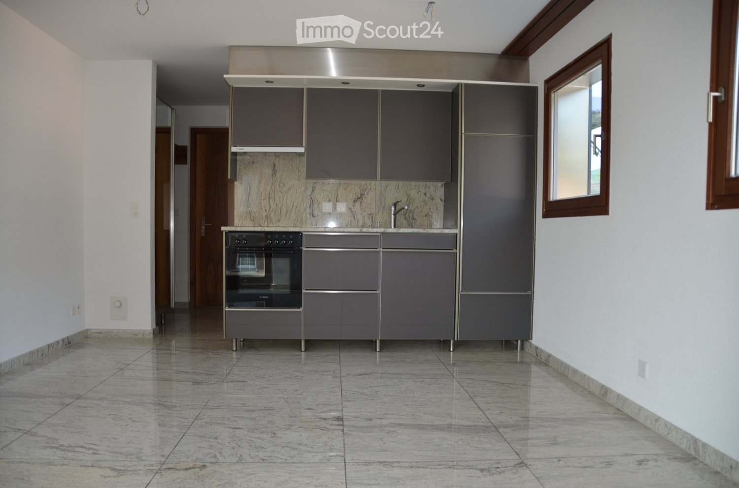 Gray kitchen cabinets, stainless steel countertop, built-in oven, under-cabinet lighting, marble flooring