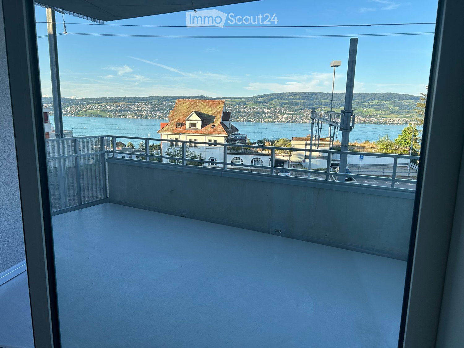 An outdoor balcony, metal railings, lake view, sky view, mountain view