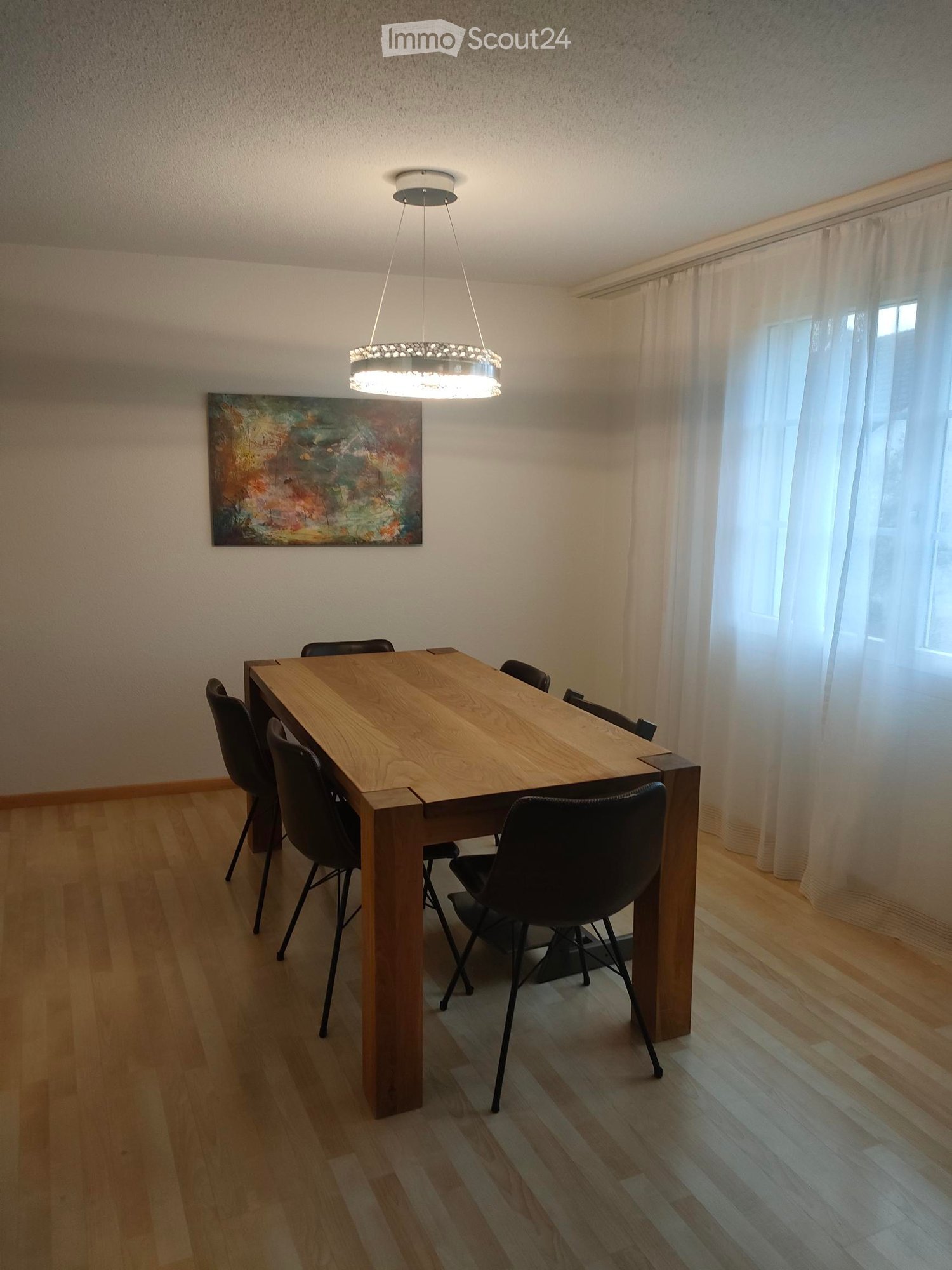 Dining room: wooden dining table with 6 chairs, modern chandelier, large window with white curtains, modern painting on the wall