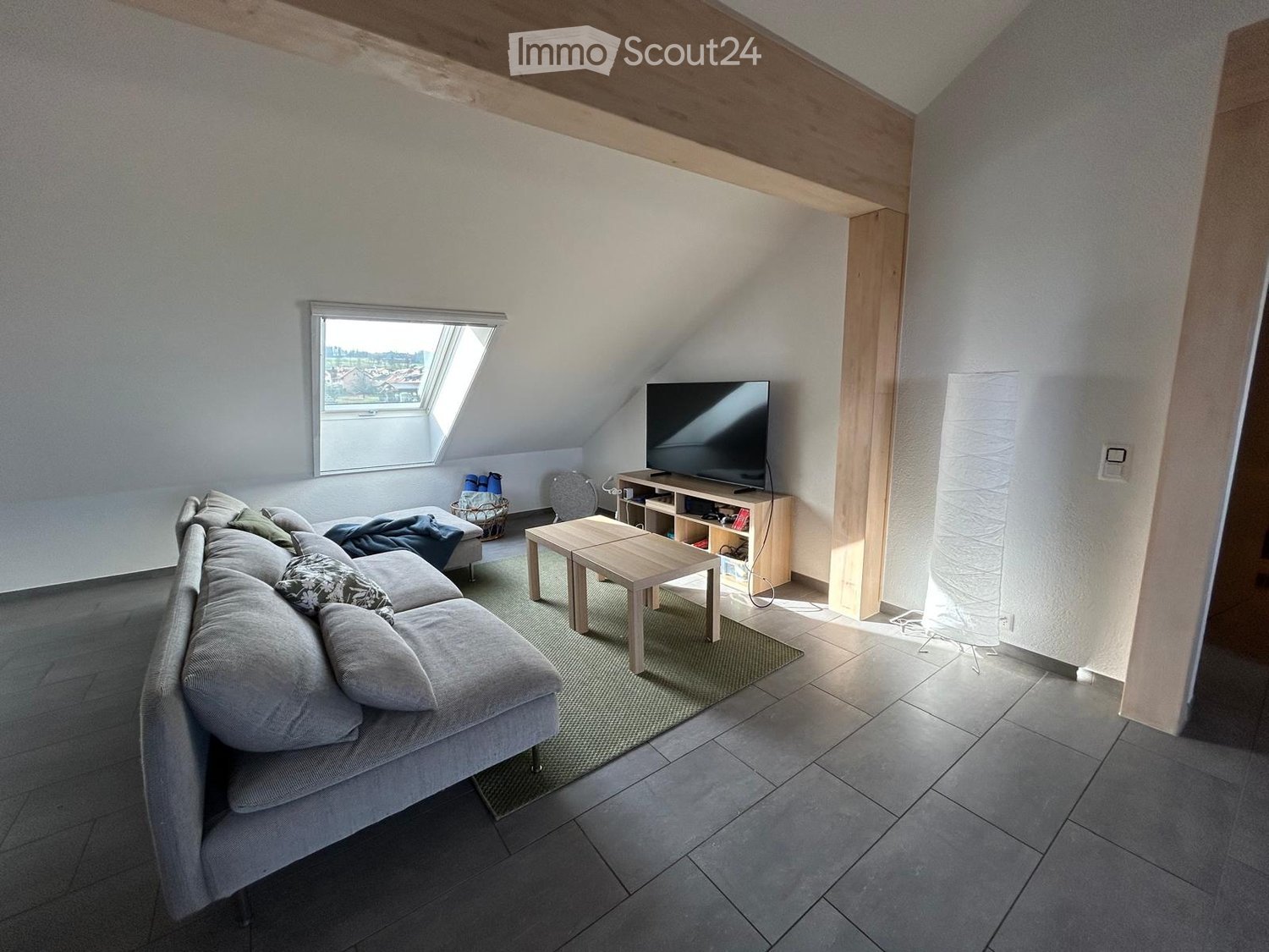 living room with sofa, table, rug, flatscreen TV, wooden beam