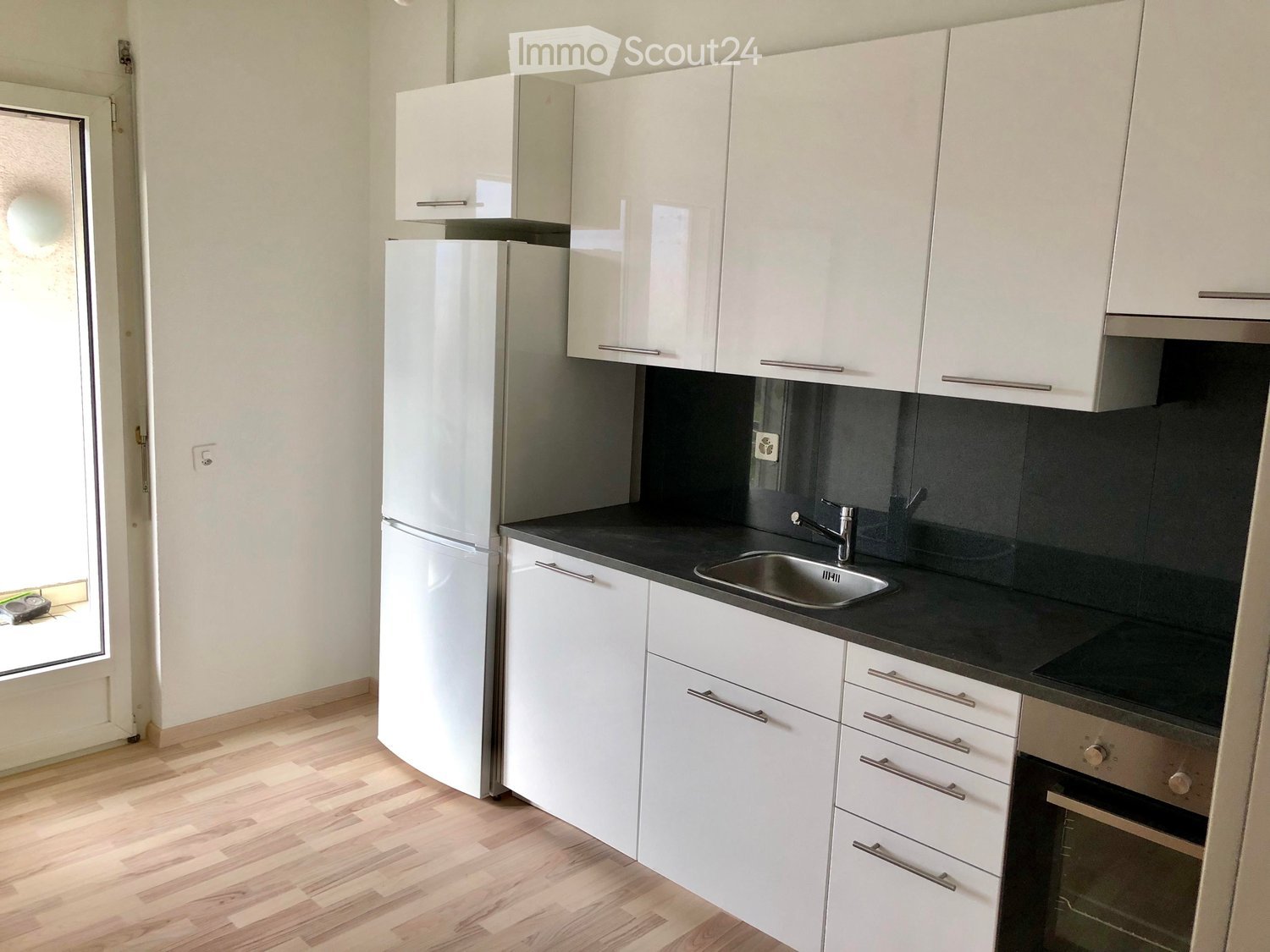 kitchen with a white fridge, white cabinets, dark countertops, a stainless steel sink, stove and oven, a glass door to the hallway, and wooden floor