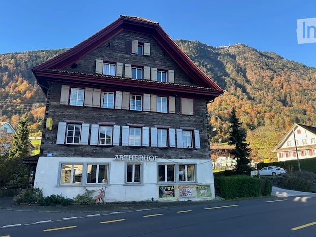 2 story house, red roof, white windows, deer statue in front, mountains in background