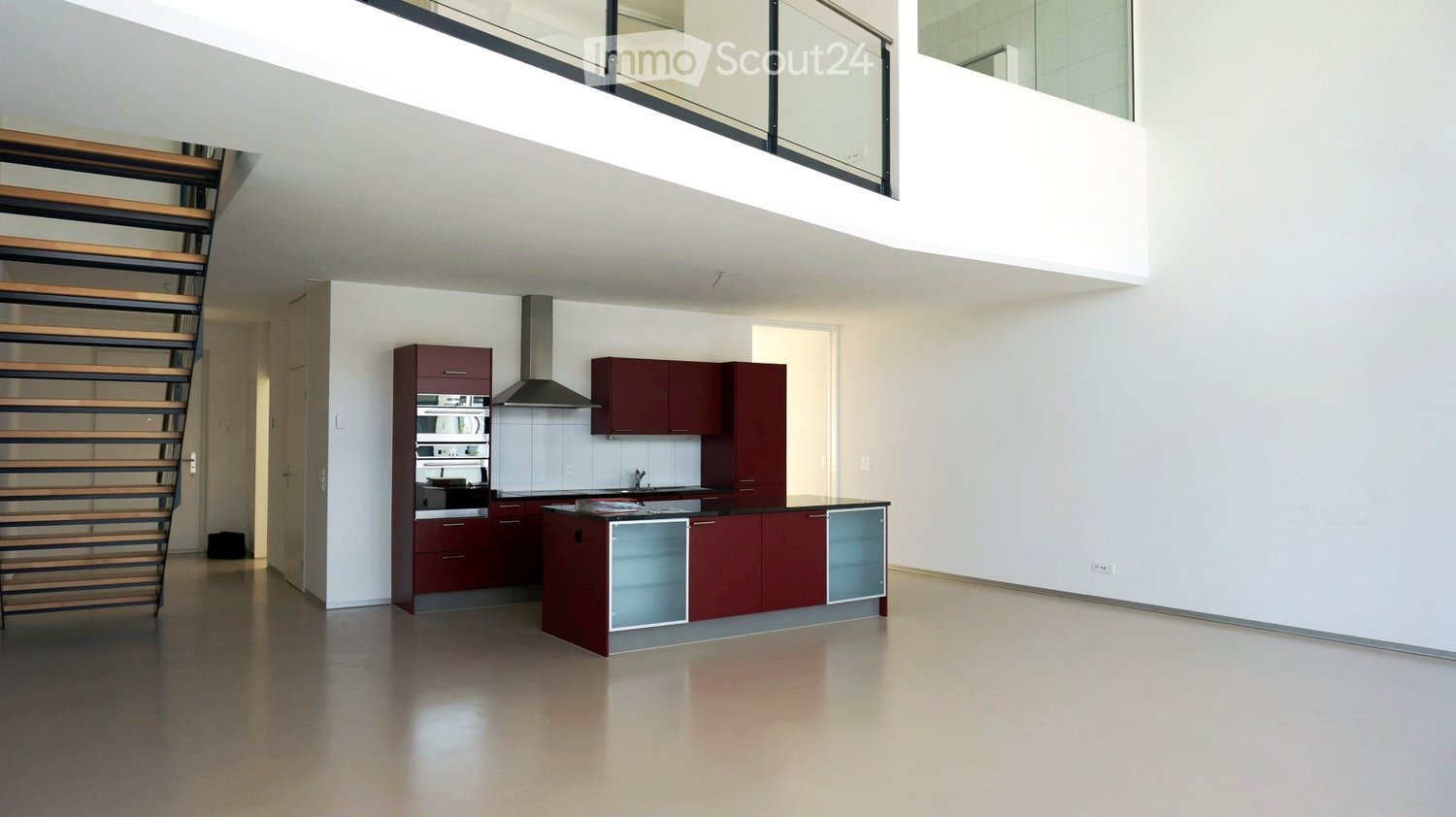 Large open kitchen with appliances, wine cabinet, large window, staircase