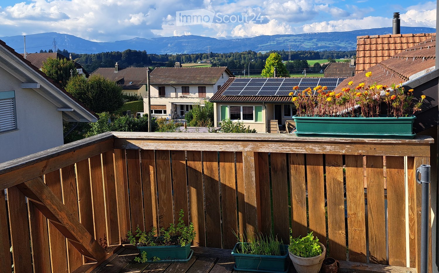 wooden balcony with view, potted plants, solar panels on house