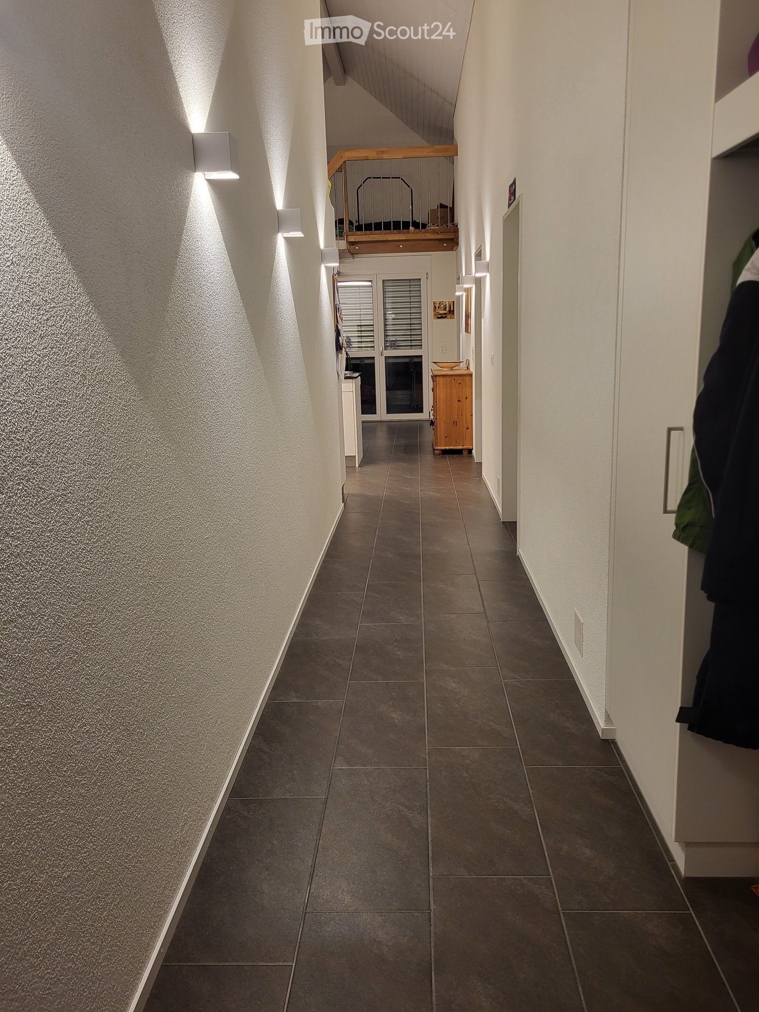 white walls, brown tiled floor, wall lamps, cabinets, balcony, glass doors