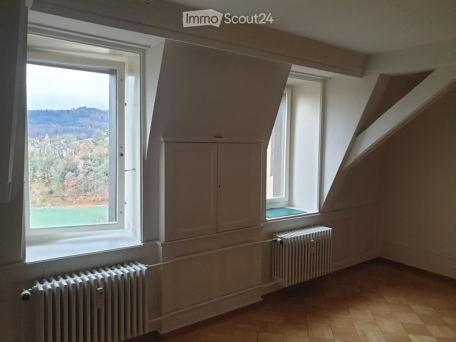 empty room, 3 large windows, wooden floor, built-in radiators, cabinets above radiators