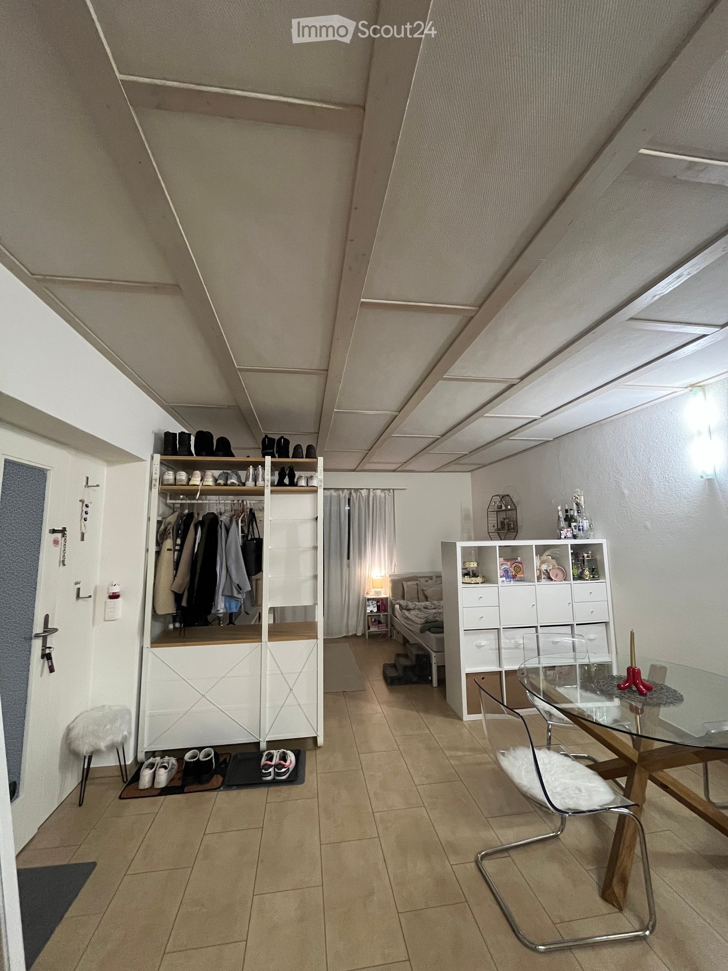 open plan space with a dining table and a bed, built-in closet, modern and minimalistic design