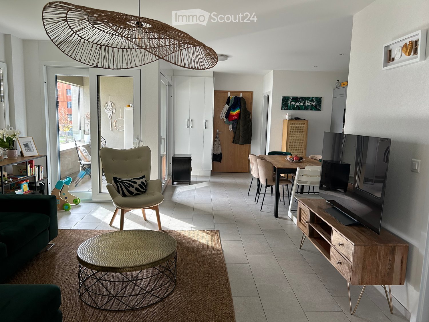 modern living room with tile flooring, furniture arrangement including a sofa, armchair, coffee table, dining table, TV, and a glass door leading to a balcony