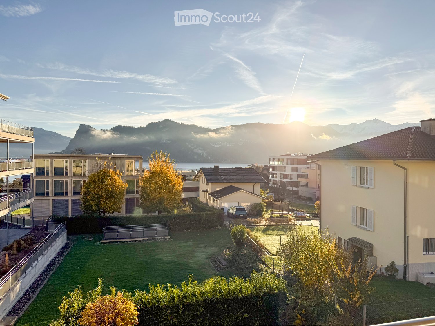 Aerial view of multiple houses with garden, mountains in the background