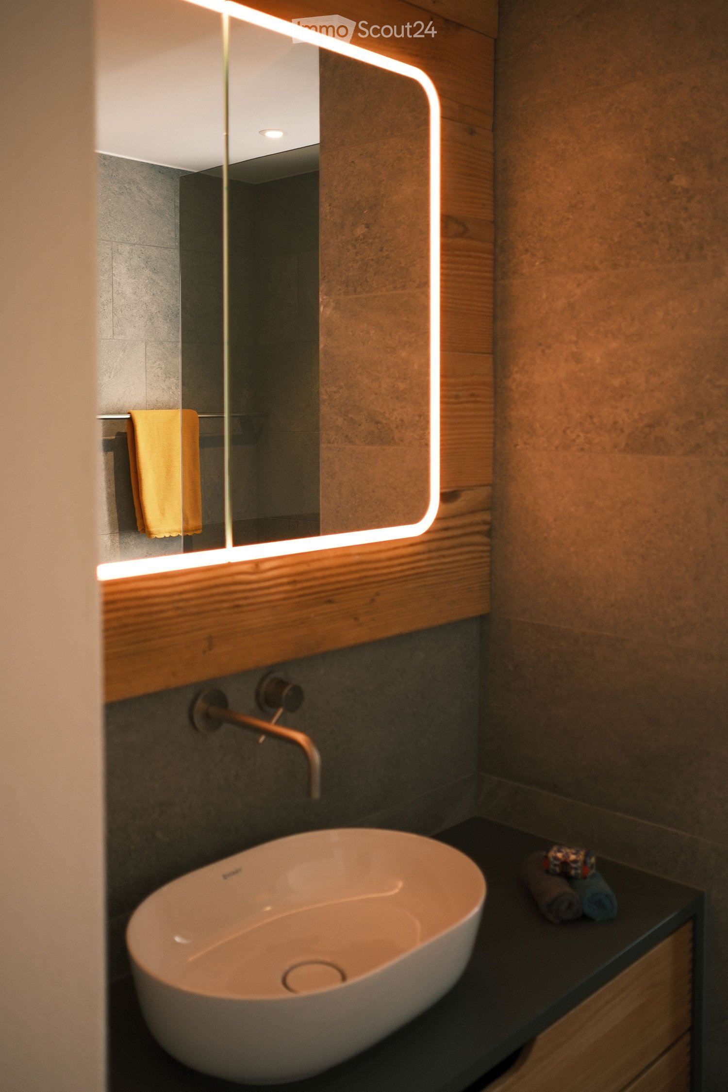 modern bathroom with white sink, large mirror, wooden shelves, bright lighting, and towel rack