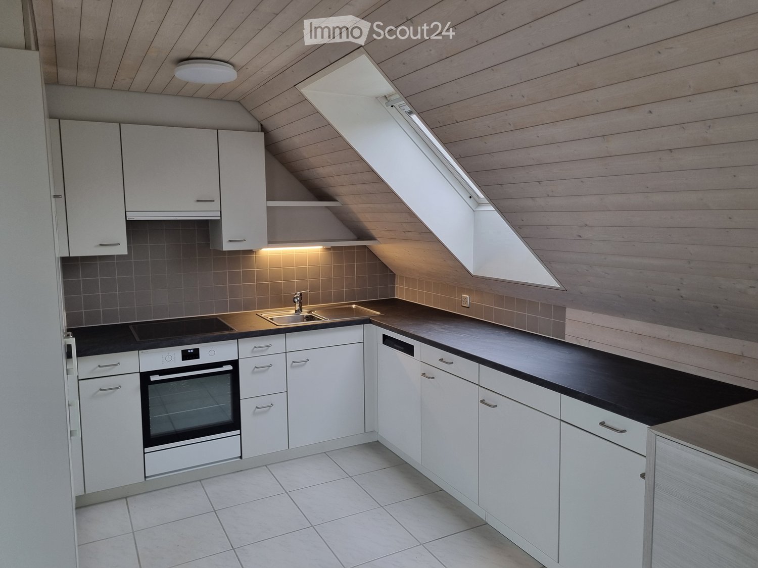 modern kitchen with white cabinets, black countertops, stainless steel sink, silver faucet, built-in oven, dishwasher, ceiling lamp, skylight, tiled floor