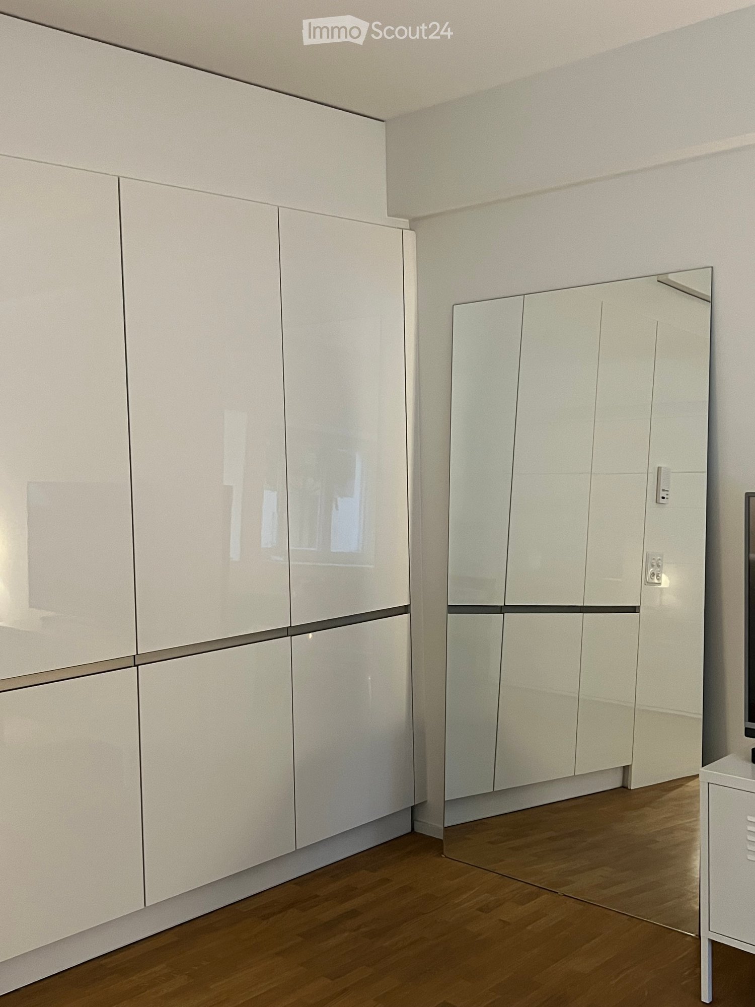 white built-in closets, large mirror, TV, wooden floors