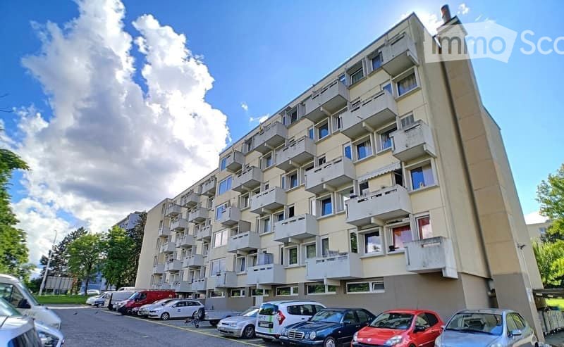 large multistory building, numerous balconies, many cars parked in front