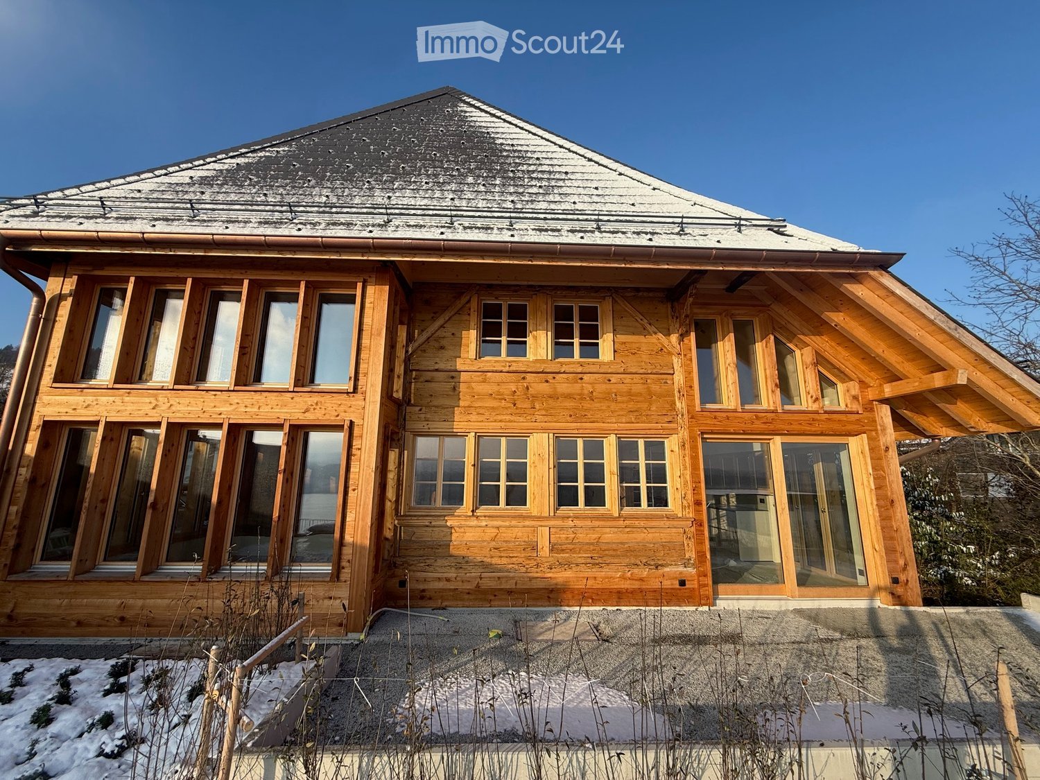 Wooden house, large windows, gable roof, covered driveway