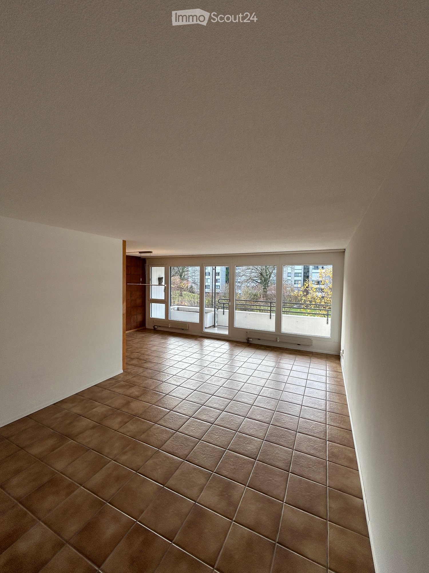 Empty room with tiled floor, white walls, sliding glass doors, balcony, city view, no furniture