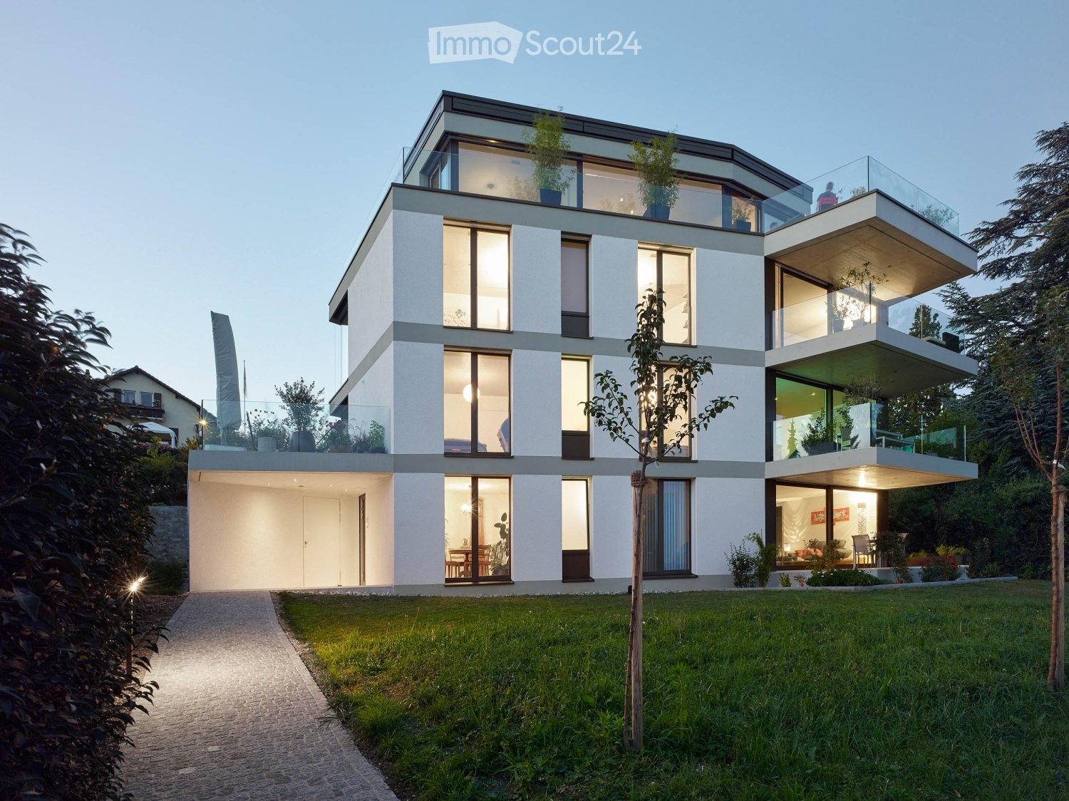 Modern white house, large windows, multiple balconies, glass railings, spacious garden, driveway