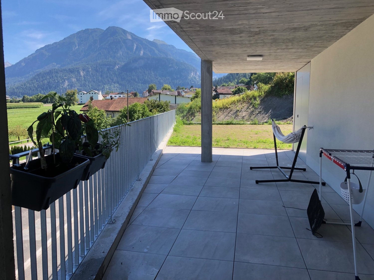 tiled floor, balcony, metal railing, mountain view, plants in pots, table, hammock