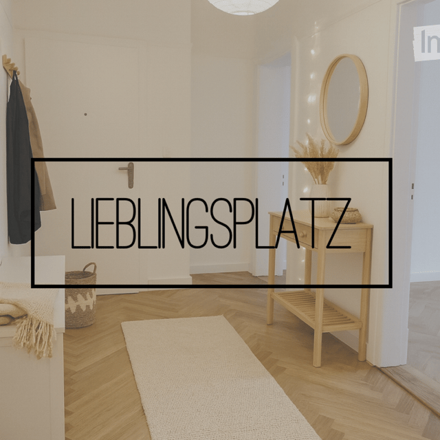 Entrance hall with wooden flooring, white walls, a hanging coat, a white rug, a wooden table with drawers, and a mirror