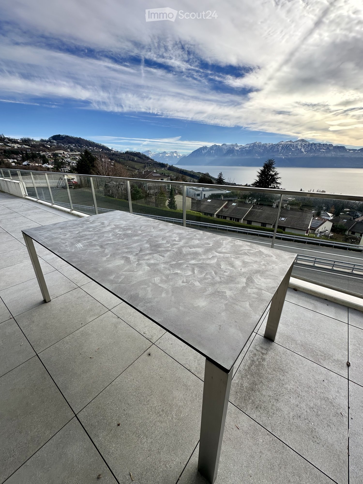 rectangular concrete table with metal legs, surrounded by a glass railing