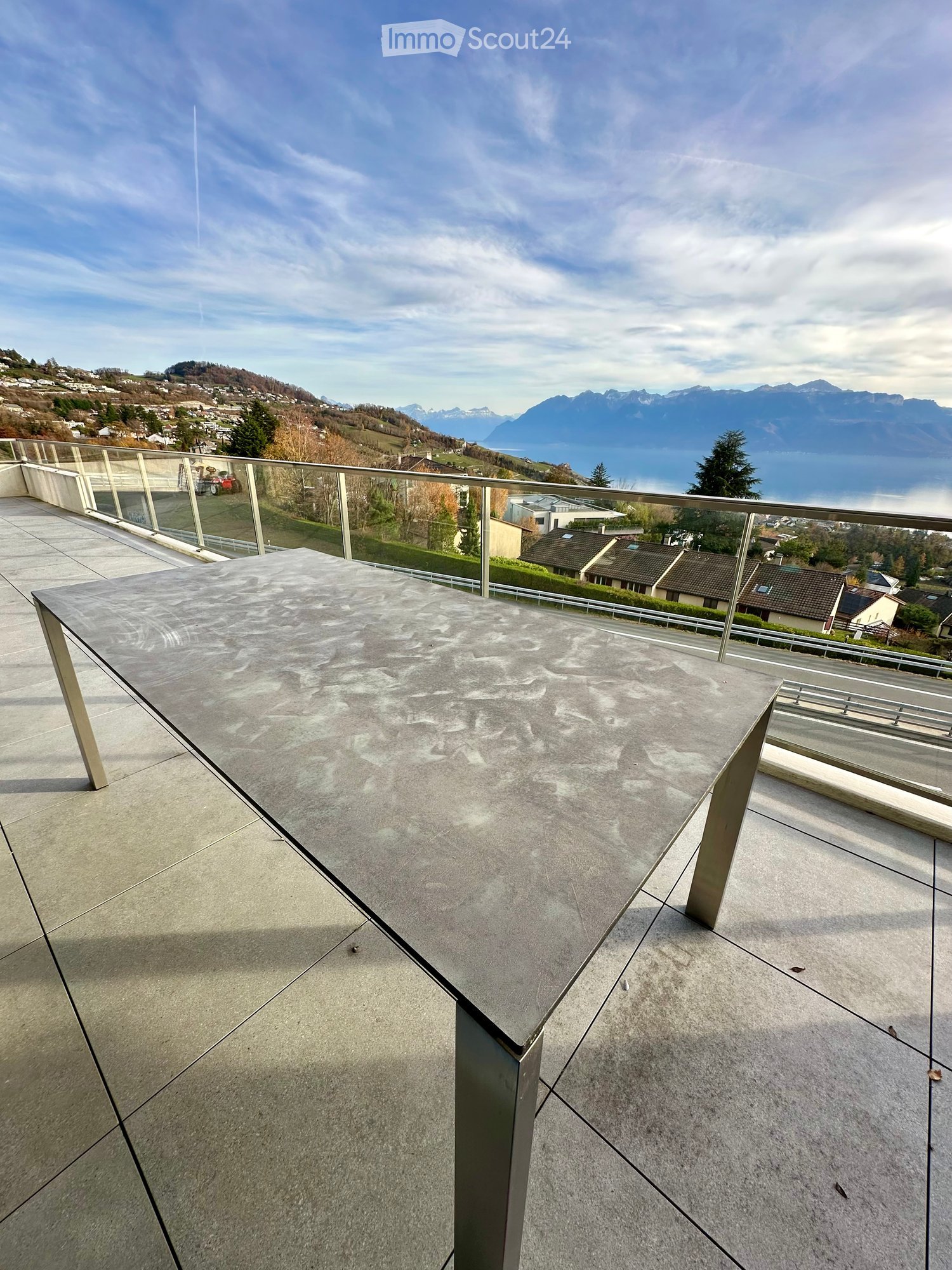 metal table, metal railing, grey tiles, open outdoor space, mountain view