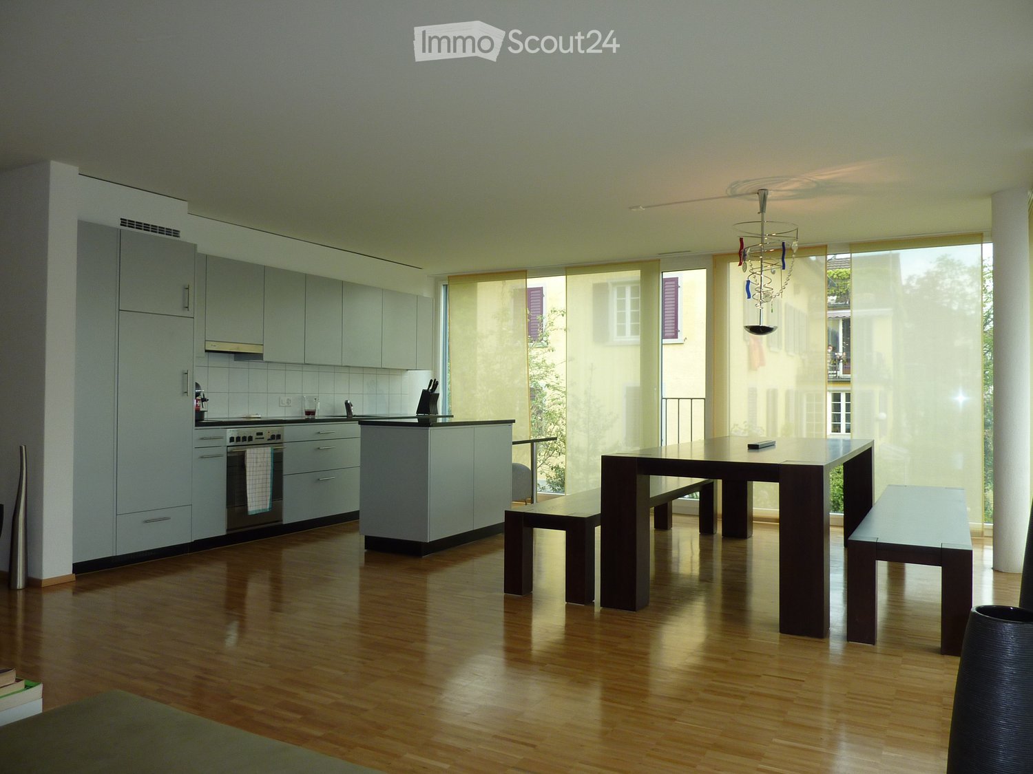 open kitchen, white cabinets, black countertops, black table, white sliding glass doors, balcony, modern chandelier